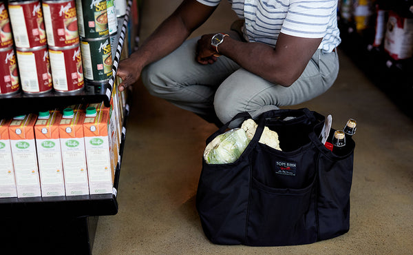 The Truck filled with groeceries while a person pulls something from a store shelf.